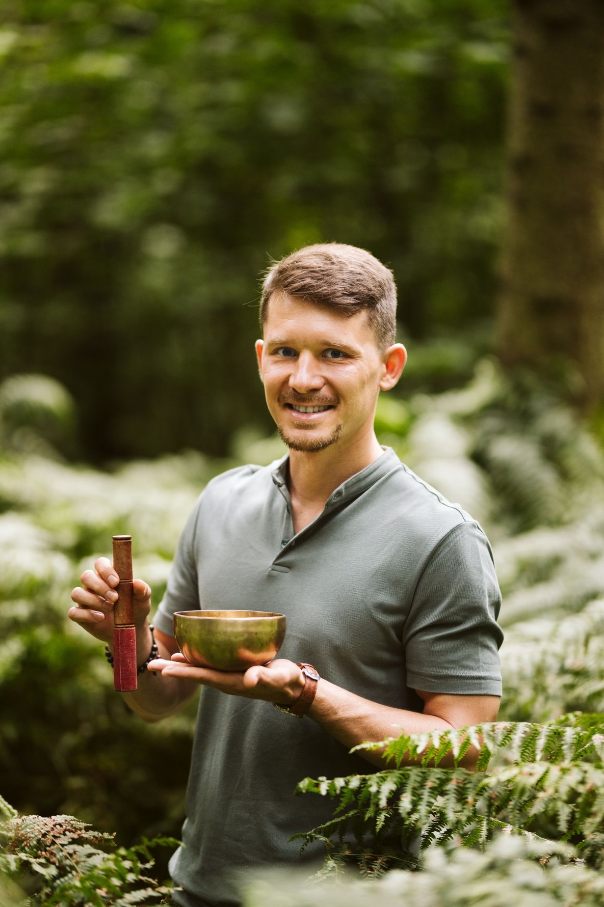 Michał Kutzner z misą dźwiękową w dłoniach w lesie